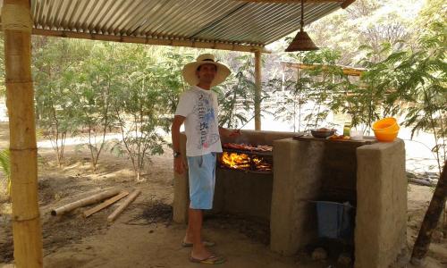 卡诺阿斯德蓬萨尔Camping Matufa Mancora的站在壁炉旁戴帽子的人