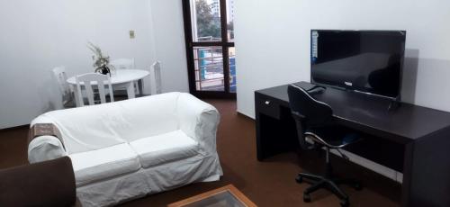 乌鲁瓜亚纳Praça Residence的客厅配有书桌、电视和椅子