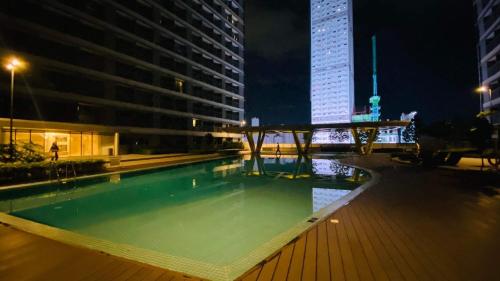 马尼拉Cozy 1Br with Netflix & Balcony Pool View Condo的一座高楼,晚上有一座游泳池