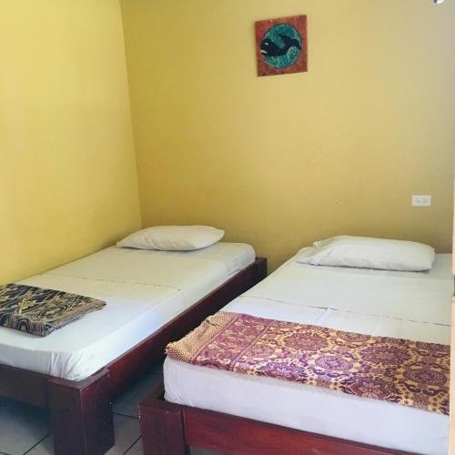 洛佩斯港Hostal Machalilla的黄色墙壁客房的两张床