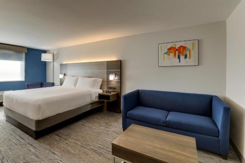 肯纳Holiday Inn Express Kenner - New Orleans Airport, an IHG Hotel的酒店客房,配有床和蓝色的沙发