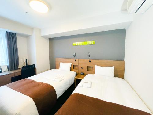 札幌札幌薄野微笑尊贵酒店的一间设有两张床的客房,墙上有标志