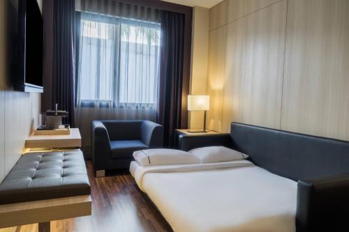 塞维利亚塞维利亚市万豪AC酒店的酒店客房配有床、沙发和椅子