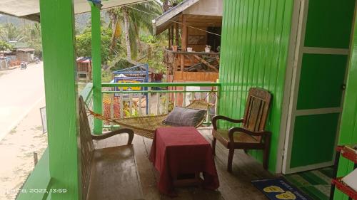 ItaytayUstaris Homestay的凉廊上的绿色房屋,配有吊床