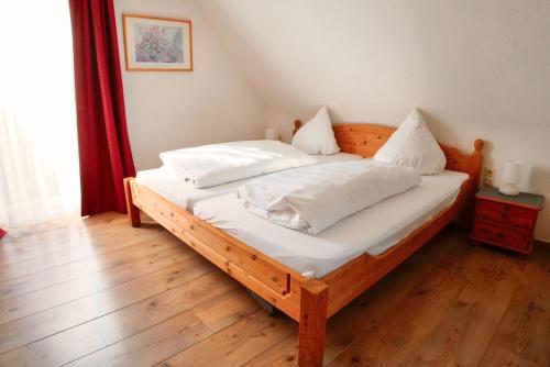 蒂蒂湖-新城希尔瓦尔德酒店的一间卧室配有一张带白色床单和枕头的木制床。