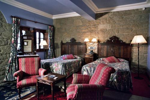 拉瓜迪亚科亚多城堡酒店的一间卧室配有两张床和一张桌子及椅子