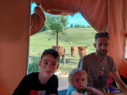 TieltSheepinn de geul的一名男子和两名儿童坐在一个有牛的帐篷里