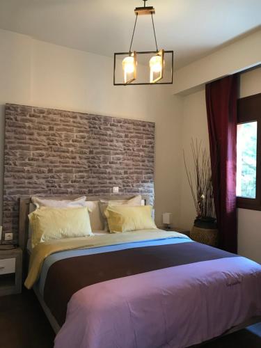 卡兰巴卡Villa Under Meteora的一间卧室设有一张带砖墙的大床