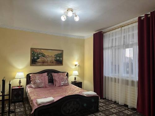 努库斯Guest house "NIKA", Nukus的一间卧室配有床和红色窗帘的窗户