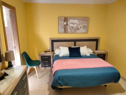 Bembribe纽弗阿隆索旅馆的一间卧室配有一张床、一张桌子和一把椅子