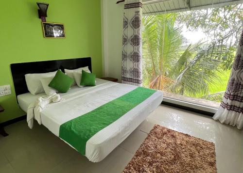 蒂瑟默哈拉默Village Mango Resort Yala的一间卧室设有一张带绿色墙壁和窗户的床。