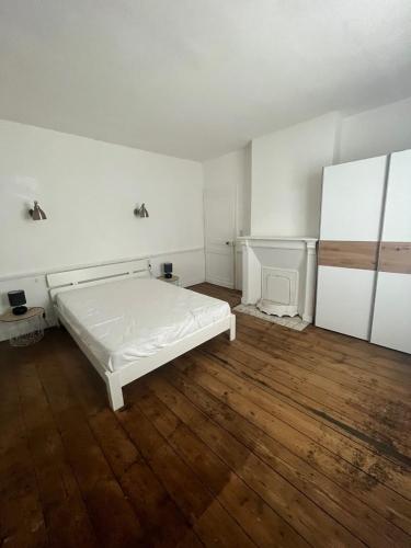 DoudevilleGite les colombages的一间铺有木地板的白色卧室,配有一张床