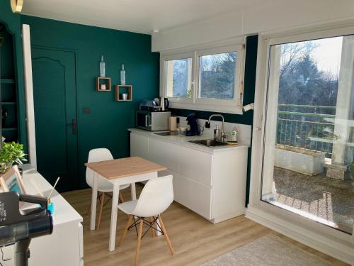 蒙贝利亚尔Appartement avec terrasse et parking gratuit accolé的厨房设有绿色的墙壁和桌椅