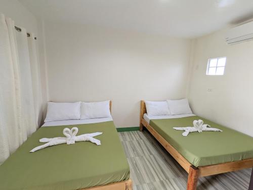 邦劳Charlina Inn Panglao的绿白色客房内的两张床