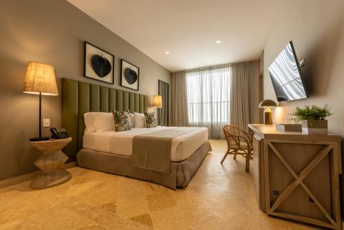 卡塔赫纳Madisson Boutique Hotel Cartagena的一间卧室配有一张床、一张桌子和一张桌子