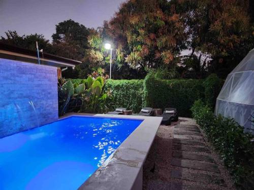 瓜纳卡斯特Ubuntu Glamping的夜晚后院的蓝色游泳池