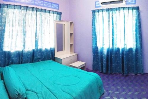 吉隆坡Tatami Homestay UIA Gombak的一间卧室配有绿色的床和蓝色窗帘