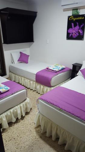 比亚维森西奥Casa Villavicencio的带紫色枕头的客房内的三张床