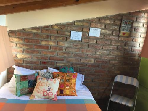 戈多伊克鲁斯Departamento Privado para dos personas en Mendoza的一间卧室设有砖墙和一张带枕头的床