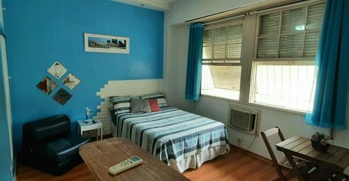 里约热内卢Sweet Studio Lapa的一间拥有蓝色墙壁的卧室,配有一张床和一张桌子