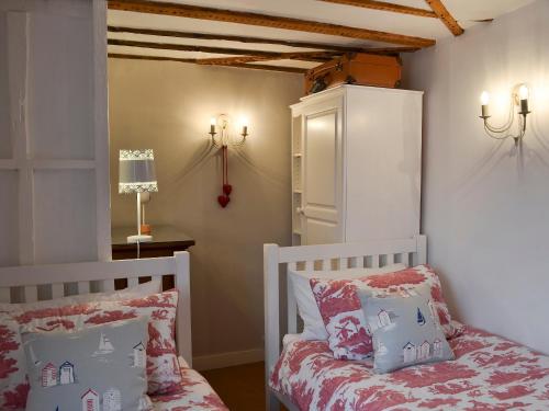 海斯廷斯茅斯度假屋的一间卧室配有两张床、一张桌子和一盏灯。