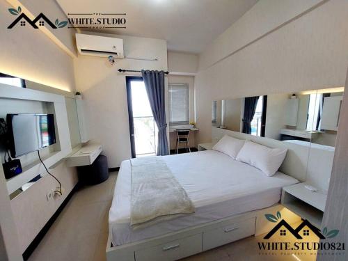 TambakosoWhite Studio Group Surabaya - WS 821 at Amega Crown Residence的卧室配有一张白色大床和一张书桌