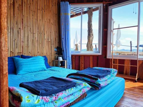 Ban KlangHomestay&ChaoleySeafoodrestaurant的一间卧室配有一张带蓝色床单的床和一扇窗户。