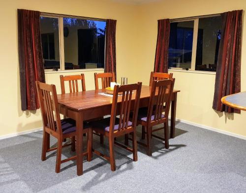 NgatakiTealuca Holiday Home的木制用餐室的桌椅和窗户