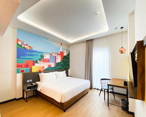 班达亚齐Alhambra Hotel Banda Aceh的卧室配有一张床,墙上挂有绘画作品