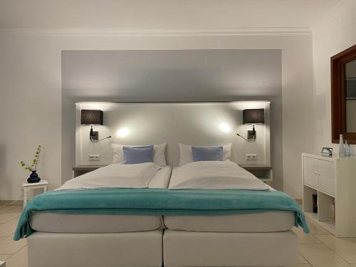 巴德贝芬森Haus Heidelerche das ThermePlus-Haus的卧室配有一张带两个灯的大白色床
