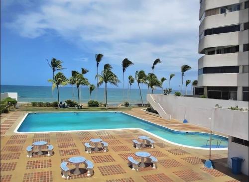 波拉马尔*Tulli Apartmentos Margarita Island*的一个带椅子和遮阳伞的游泳池以及大海