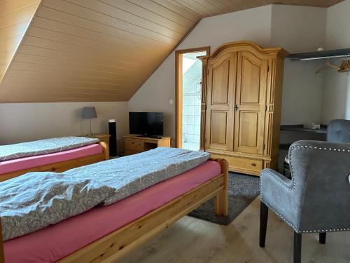 HarthausenPension Zum Paradies的一间卧室配有两张床、一个橱柜和椅子