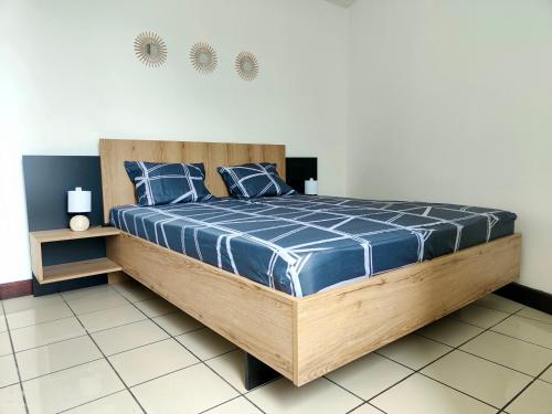 圣玛丽Appartement T2 - Sainte-Marie - 10 min de l'aéroport的一间卧室配有一张大木床和蓝色床单