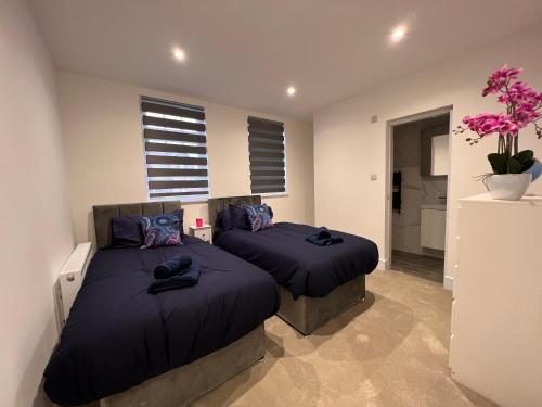亨顿Star London Finchley Lane 2-Bed Oasis with Garden的卧室内的两张床,配有紫色枕头