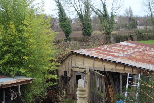 莫伯日maison d'artiste accès jardin的一座有锈色锡屋顶的古老建筑