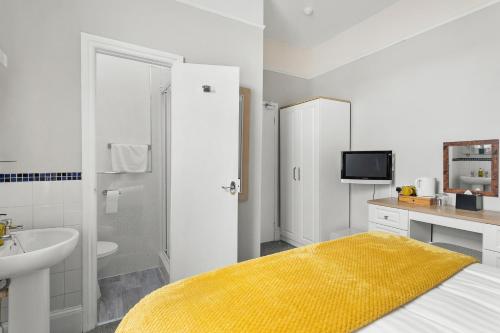托基South view的白色的浴室设有水槽和一张黄色毯子床。