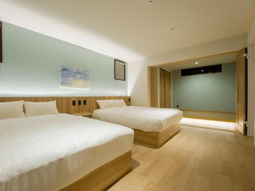 鸭川市Rakuten STAY VILLA Kamogawa Building C with Terrace and sauna Capacity of 10 persons的酒店客房设有两张床和投影屏幕