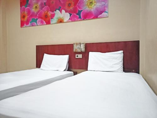 NunukanOYO 92126 Hotel Syariah Sumber Mulya Nunukan的两张睡床彼此相邻,位于一个房间里