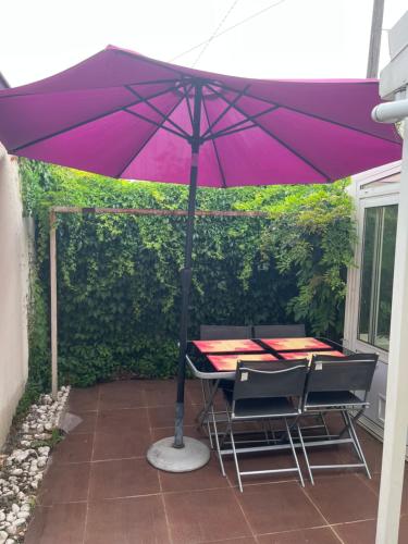 塞纳河畔维尼厄Belle maison的庭院的桌椅上方的紫伞