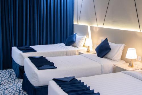 麦加سويتس المقام的两张位于酒店客房的床,配有蓝色窗帘