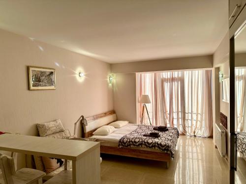 古多里Light Apartments的一间卧室配有一张床、一张桌子和一个窗户。