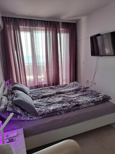 拉夫达Stensi Atlantis studia的一间卧室配有一张带紫色床单的床和窗户。