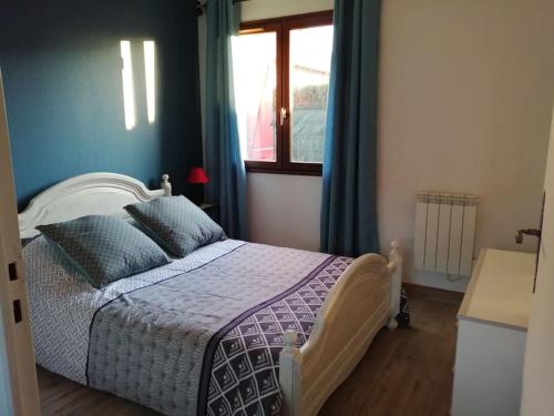 Le VaudreuilLa framboisette的一间卧室配有一张蓝色墙壁的床和一扇窗户