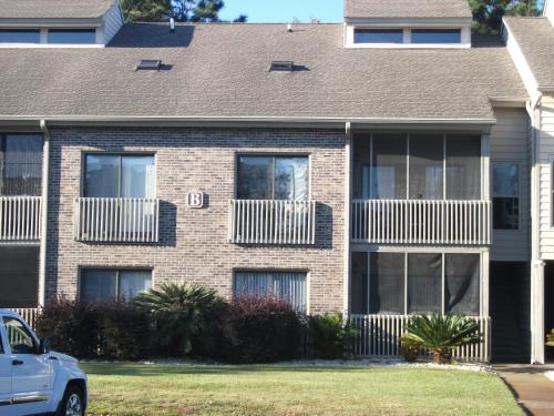 默特尔比奇Unique 2 Bedroom / 2 Bath Condo in Myrtle Beach的砖屋,有窗户,前面有停车位