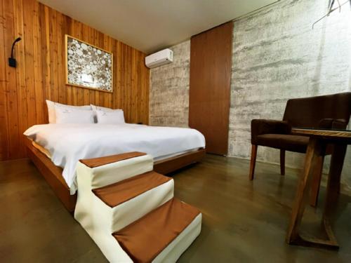 全州市Jeonju NEUE Hotel的一间卧室配有一张床、一张桌子和一把椅子