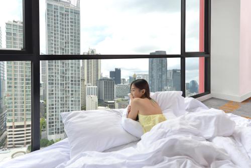 曼谷伯莱尔曼谷酒店  SHA Extra Plus的坐在窗户房间里床边的女人