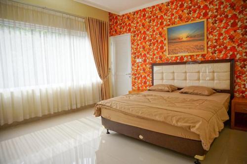 茂物Griya Kayana Inn and Villas的一间配备有床铺的卧室,位于一个橙色壁纸的房间