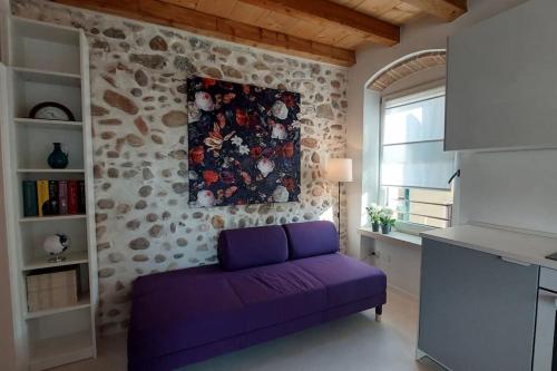 明乔河畔的瓦雷奇奥Sui Tetti di Valeggio - Holiday Apartment的石墙客房内的紫色沙发