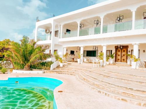 马林迪Met Beach Resort Malindi的一座白色的大建筑,前面设有一个游泳池
