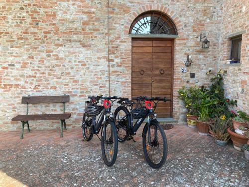 蒙泰斯佩尔托利Podere Sanripoli的两辆自行车停放在砖砌建筑旁边,该建筑设有长凳